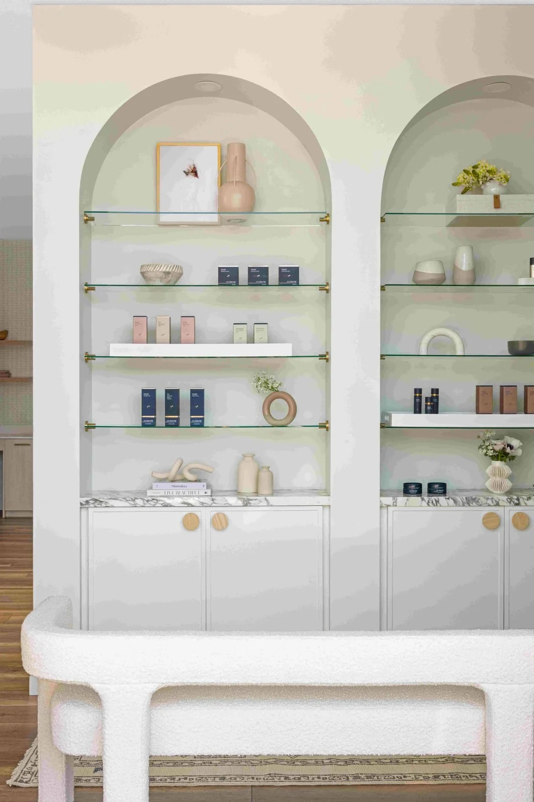 Arched alcoves with glass shelves and pale cabinets with round wood knobs