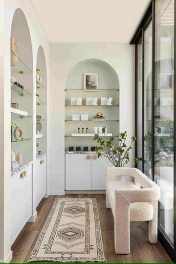 Angled view of arched display cabinets beside tall windows