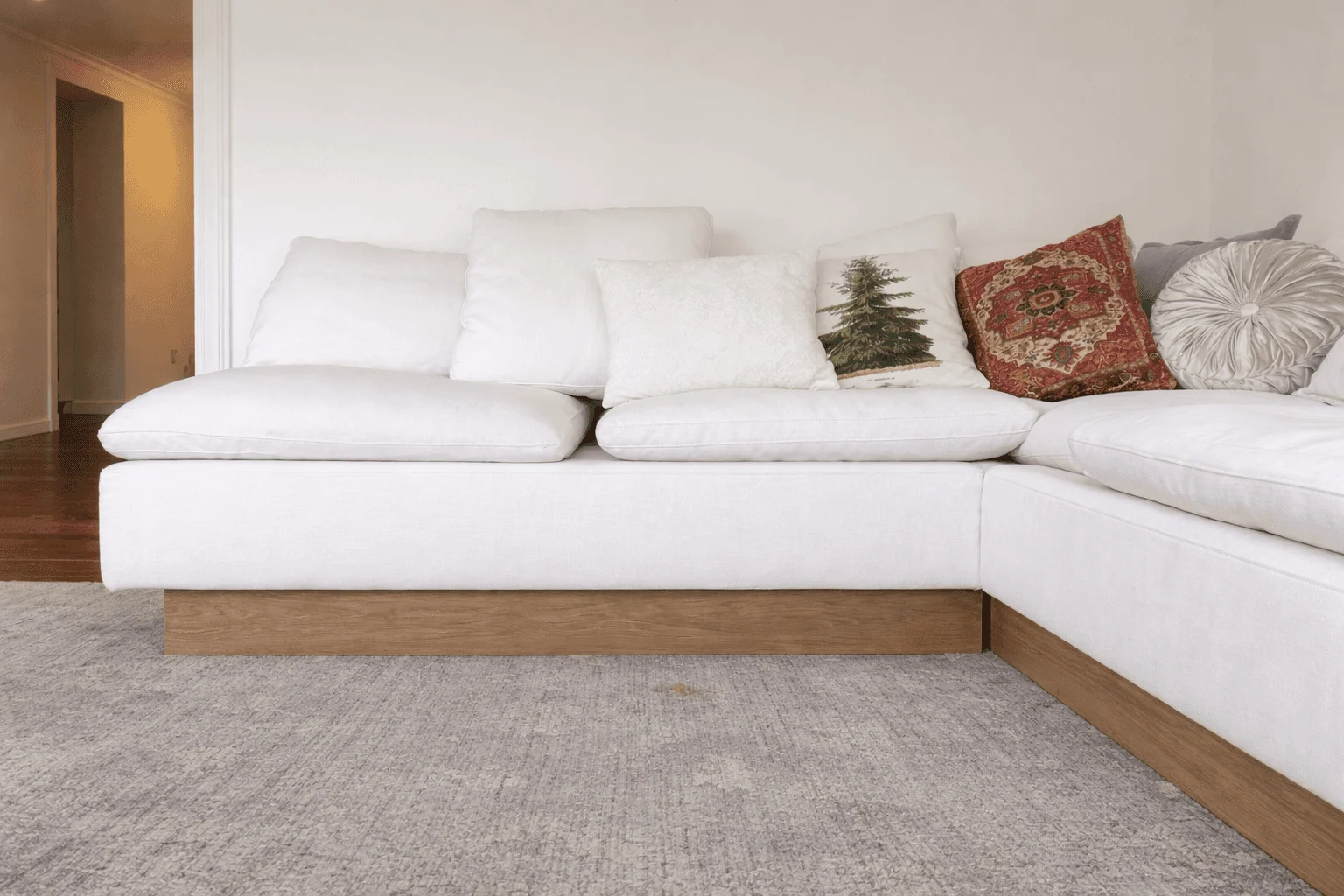 Ivory L-shaped sofa with a warm wood base and loose cushions