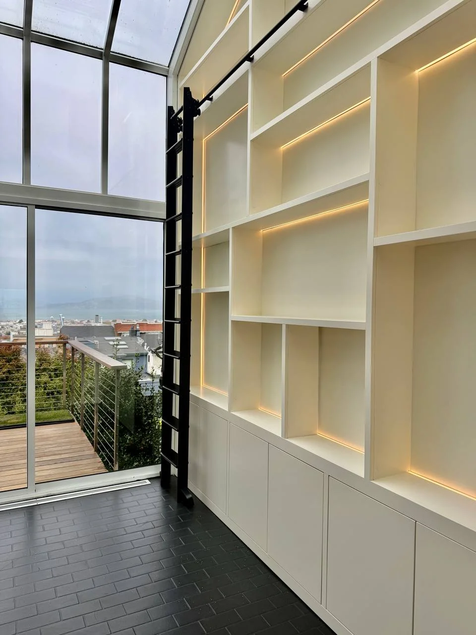 Illuminated shelving and pale base cabinets beside the window