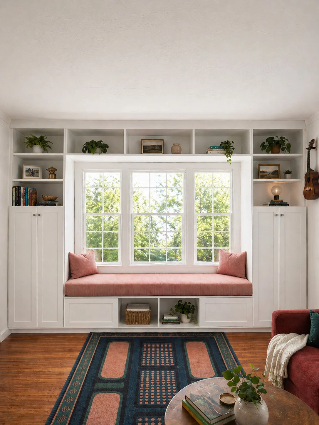 Pale built-in storage framing a window seat with a pink cushion