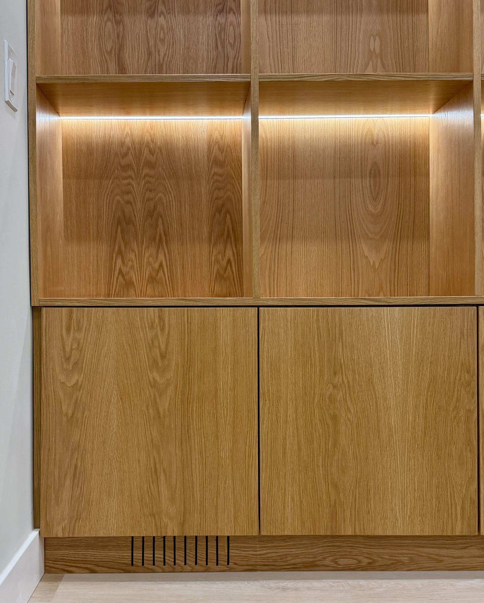 Close view of wood grain, shelf lighting, lower cabinet fronts, and a slotted base