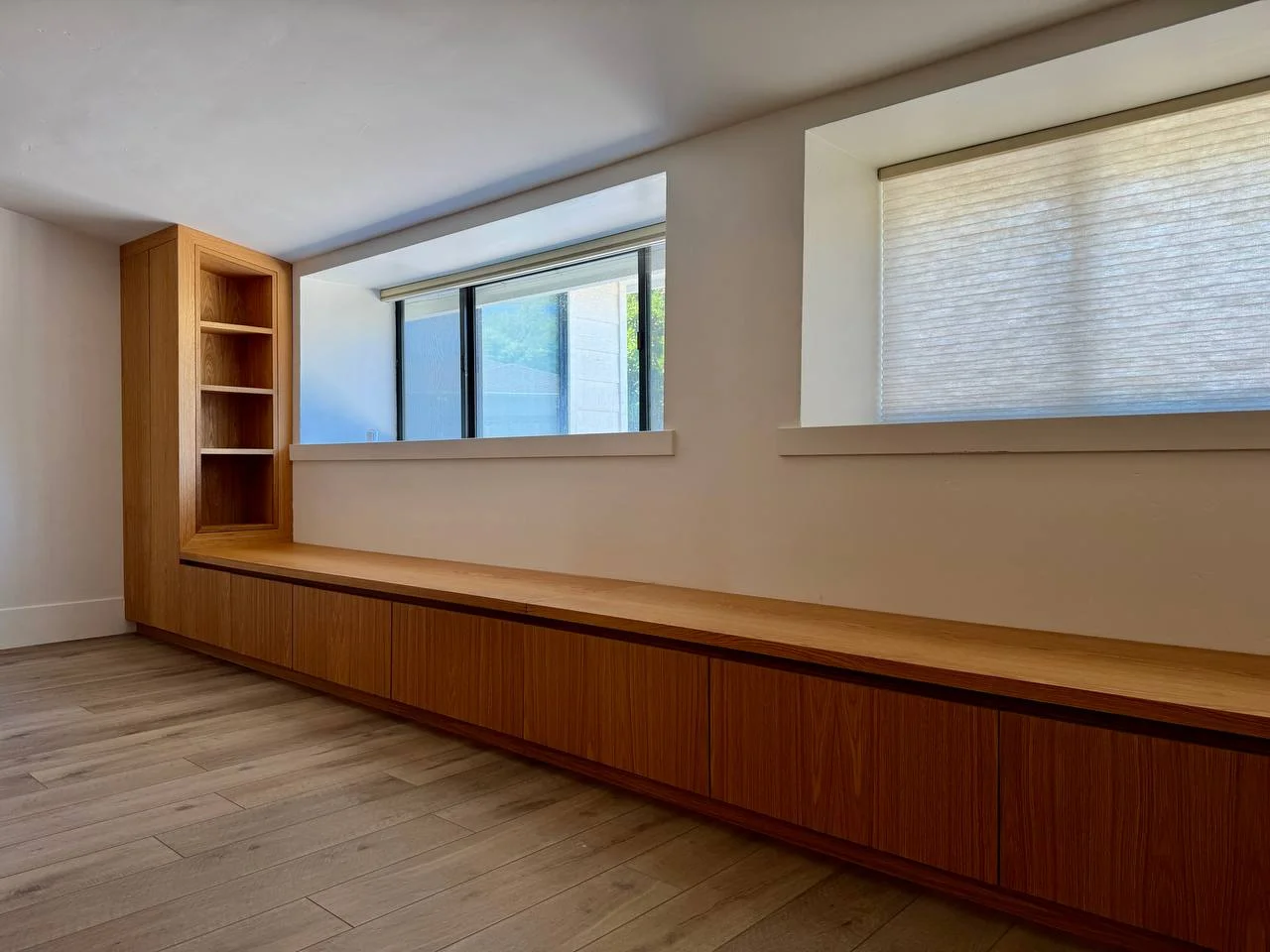 Long wood built-in beneath two windows with a tall bookcase at one end