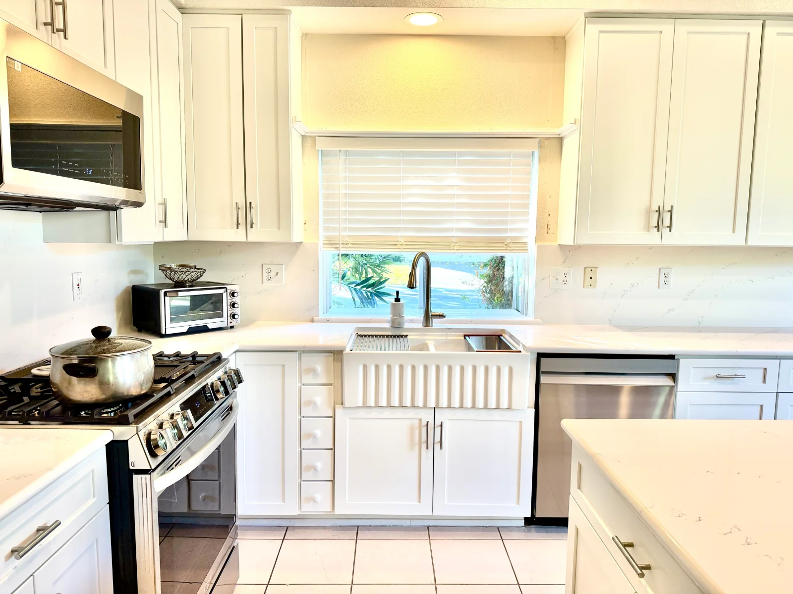 Sink wall with a fluted farmhouse sink, a narrow drawer stack, and framed cabinet doors
