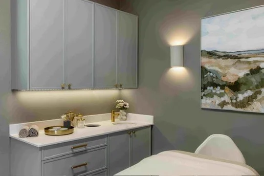Muted gray bathroom vanity with drawers, mirrored storage, and warm lighting